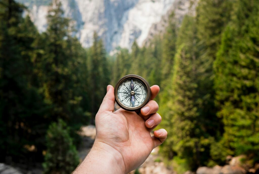 hand holding compass in woods